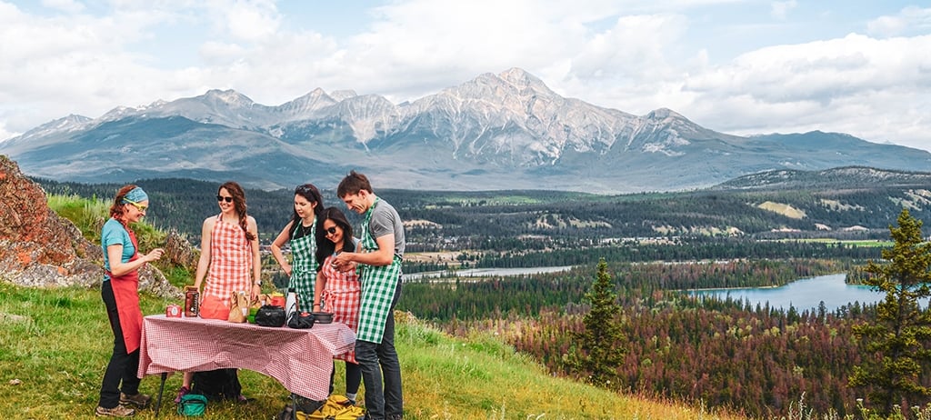 A group standing at a picnic table overlooking the mountains