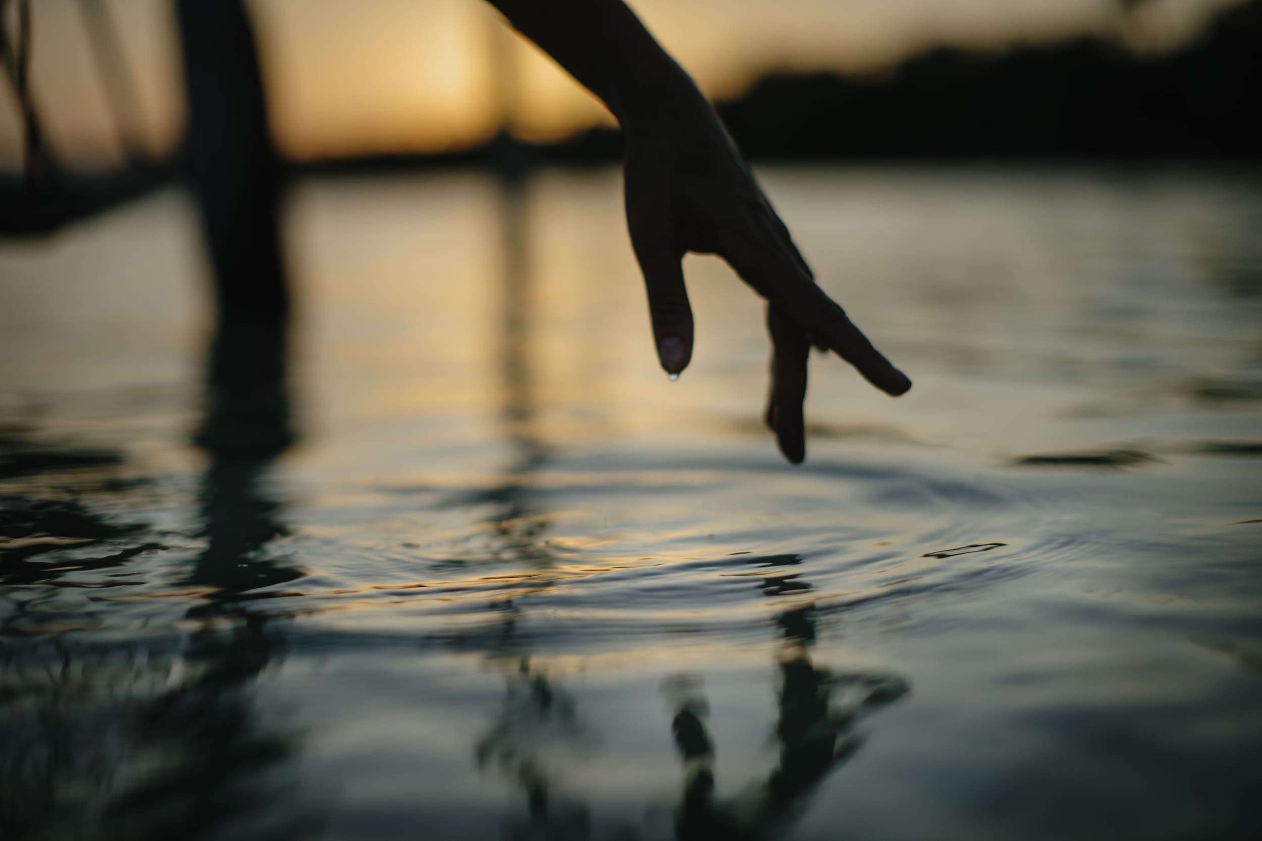 silhouette of fingers playing on water at night