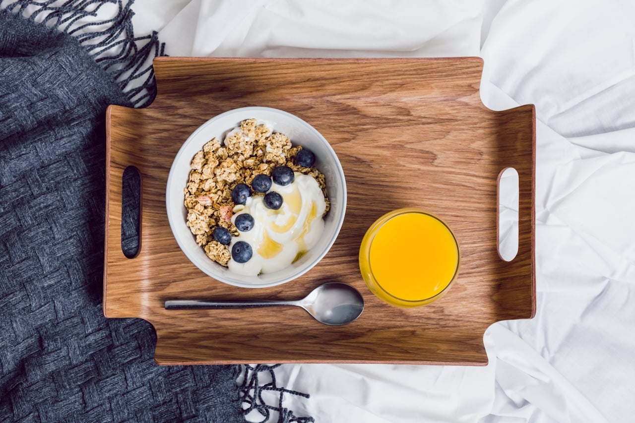 Photo of an in-room dining tray with a spoon, glass of orange juice and a yogurt bowl.