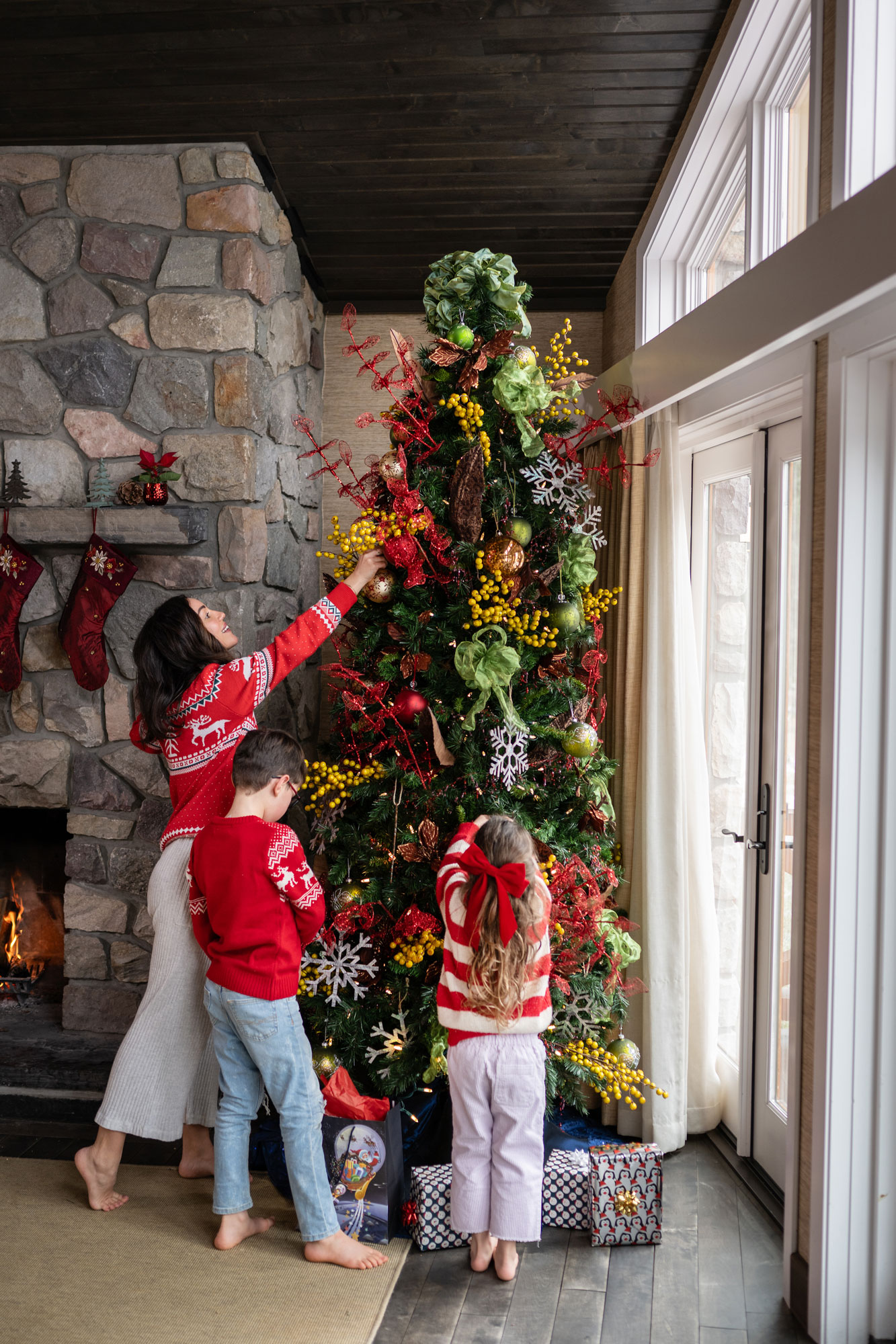 Mother, son and daughter handing ornaments on a Christmas tree in Stanley Thompson Cabin at Fairmont Jasper Park Lodge.