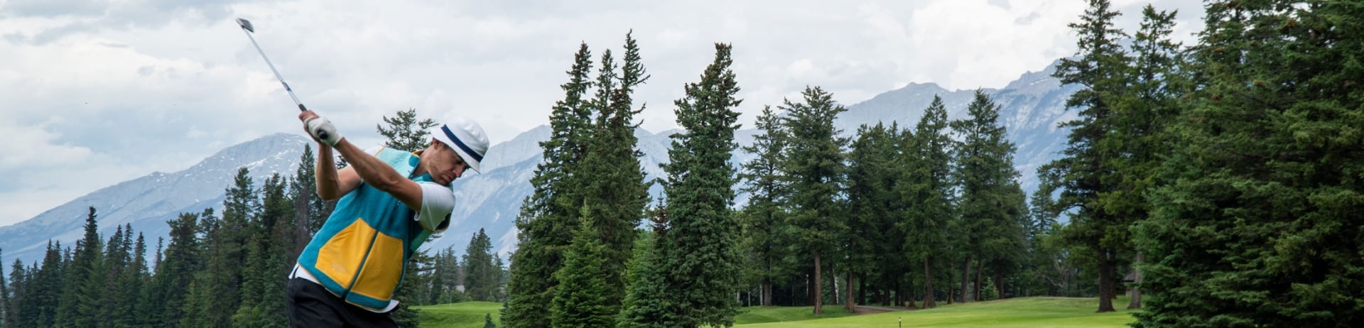 Golfer teeing up to hit the ball on the course at Fairmont Jasper Park Lodge Golf Club