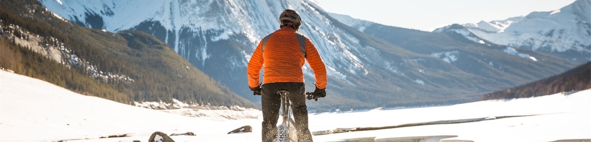A person fat tire biking in the snow surrounded by mountains