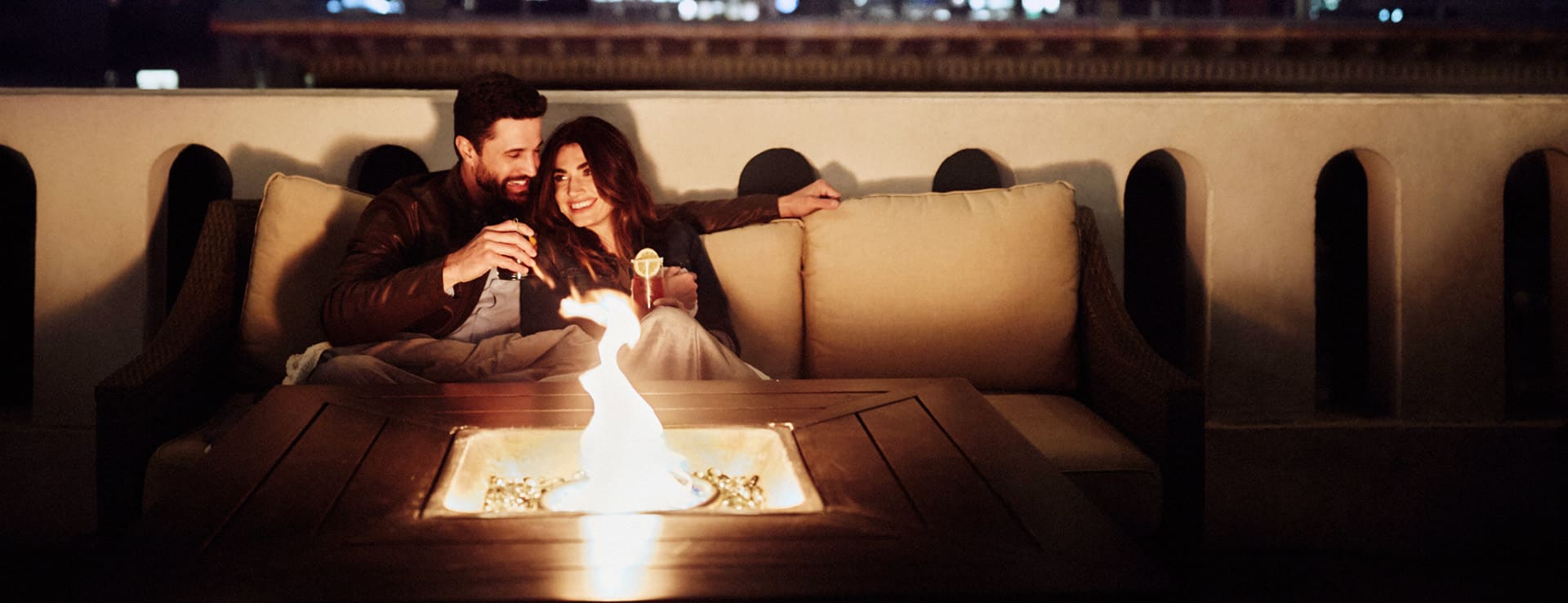 couple enjoying drinks in front of fire pit