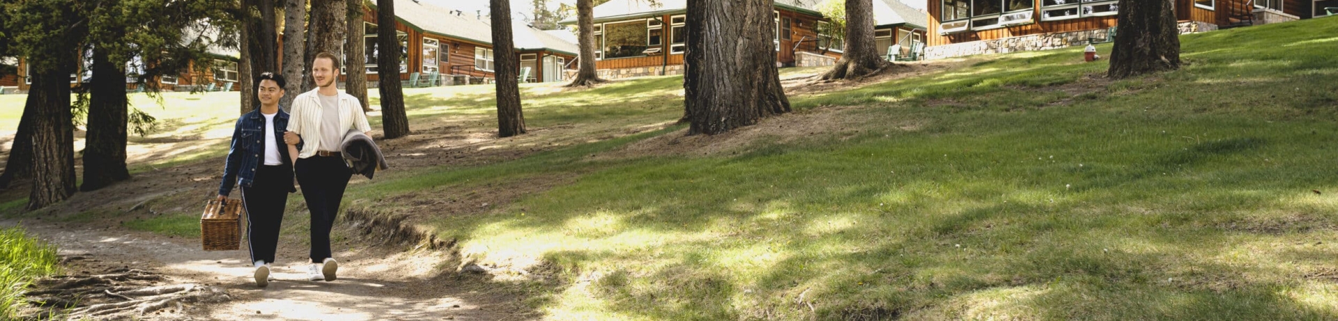 two friends walking with picnic basket in front of cabins
