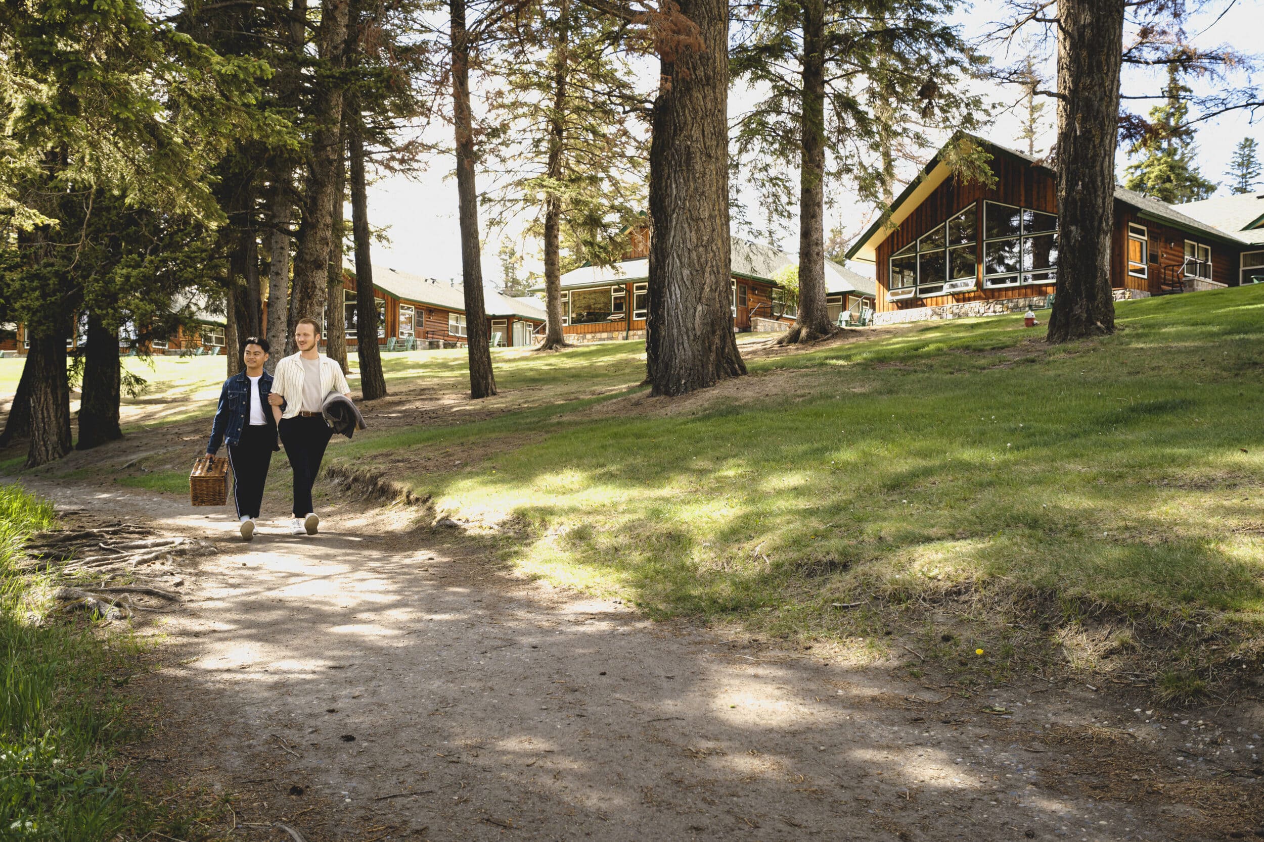 two friends walking with picnic basket in front of cabins