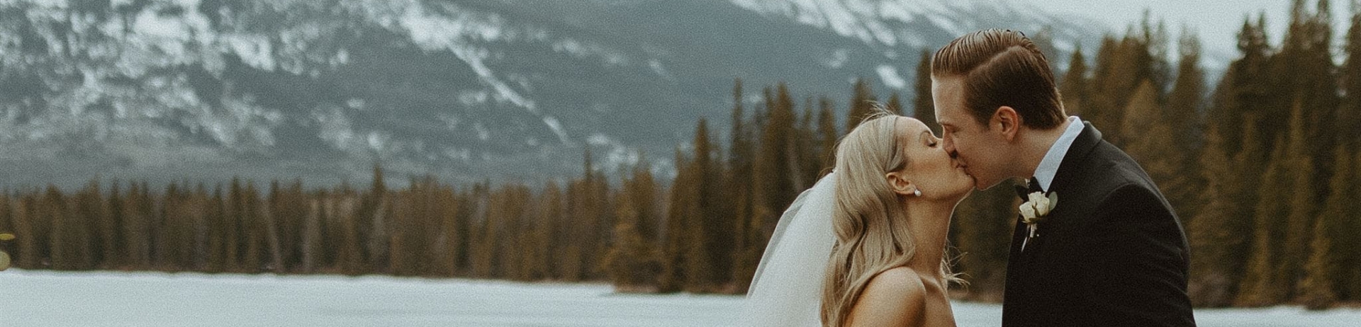 bride and groom kissing in winter by lake
