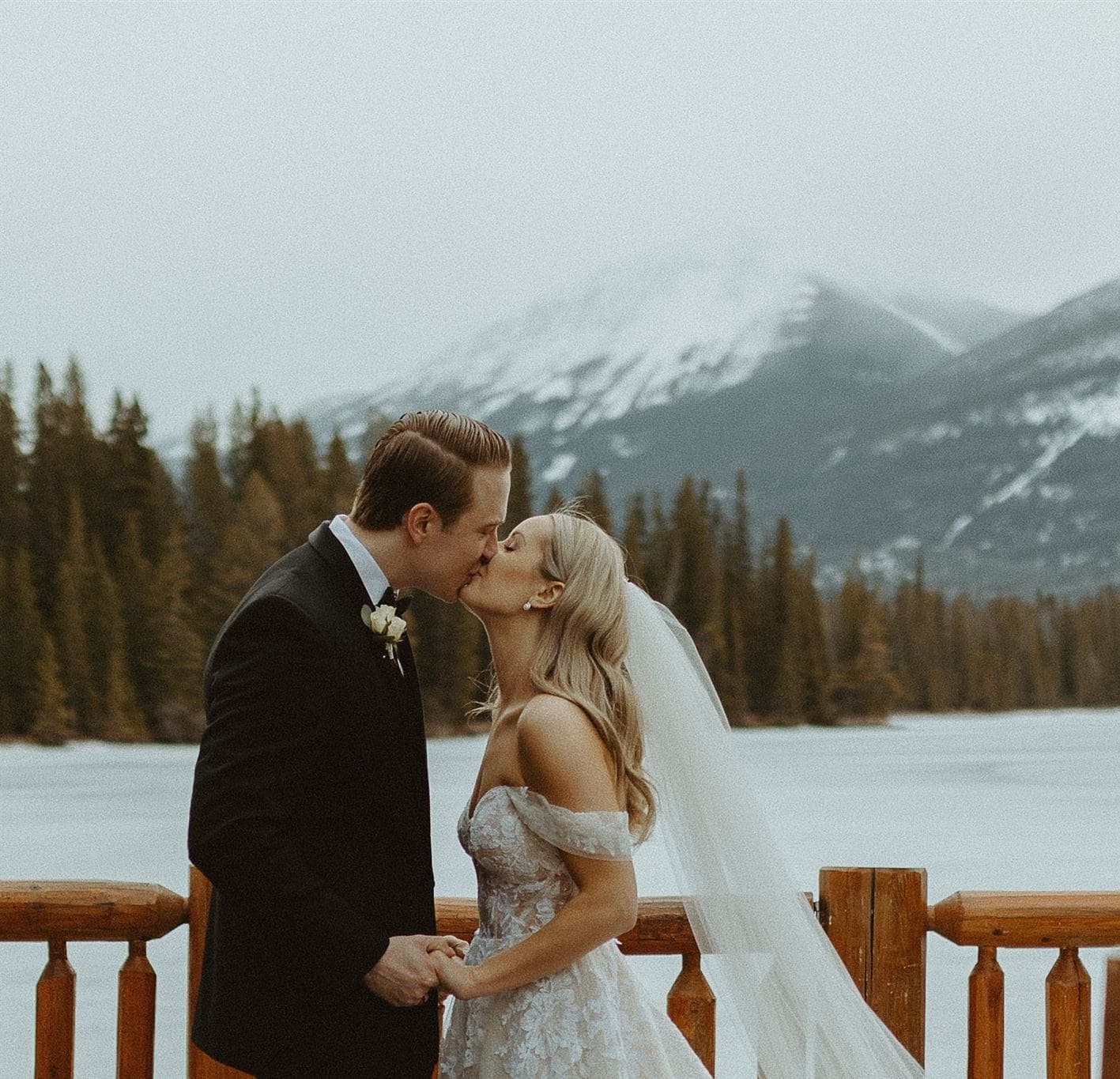 bride and groom kissing in winter by lake