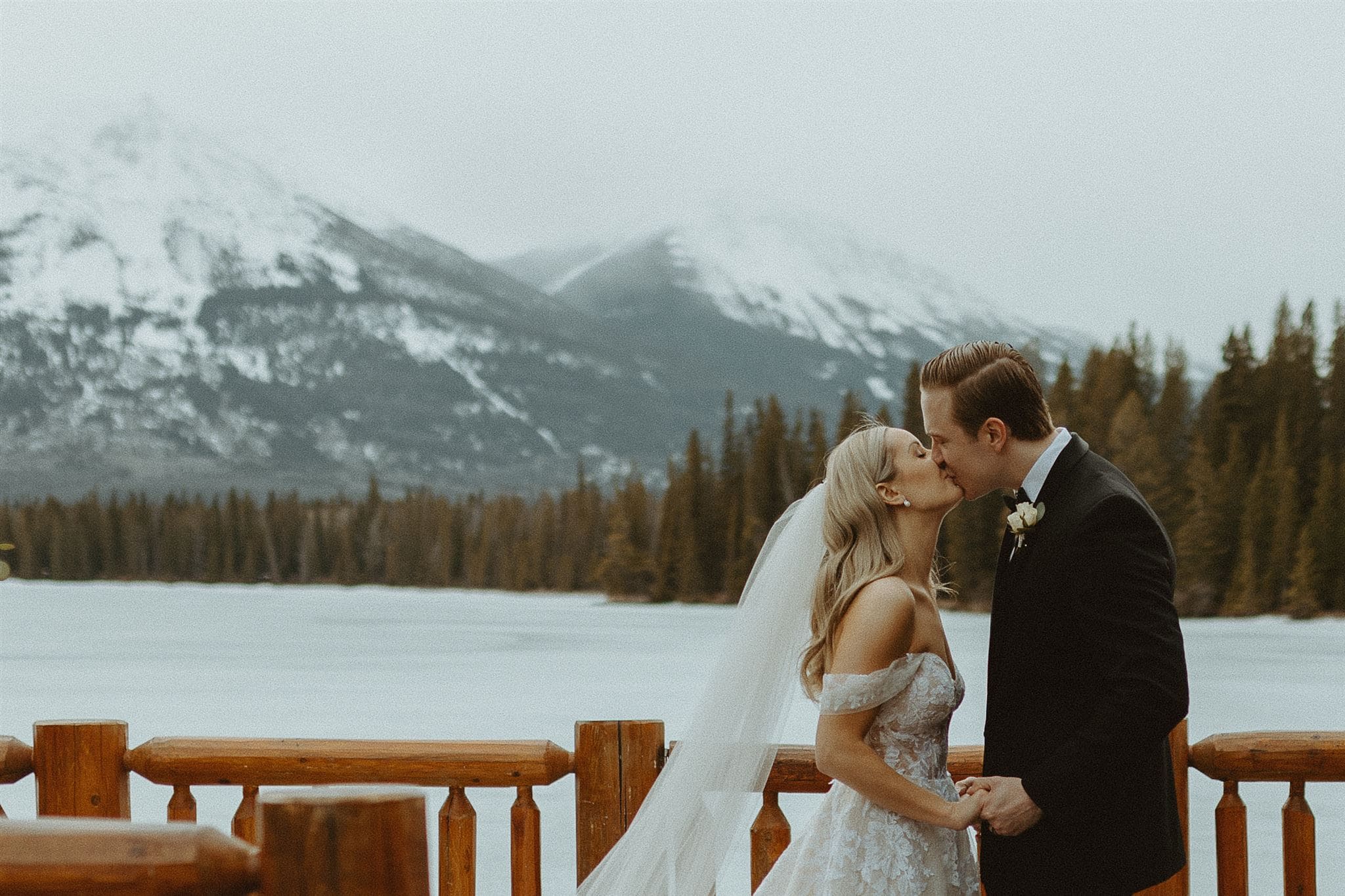 bride and groom kissing in winter by lake
