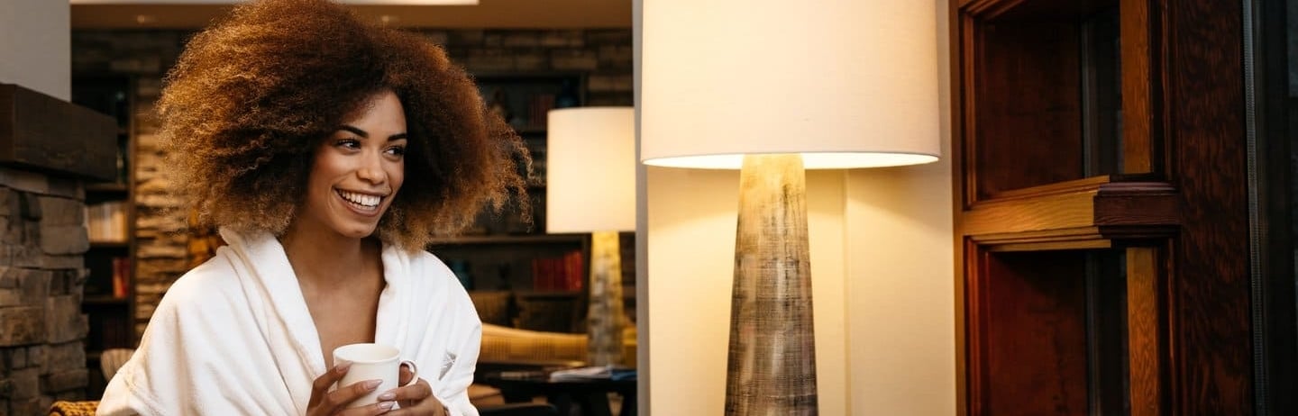 woman sitting in a chair drinking tea in her robe