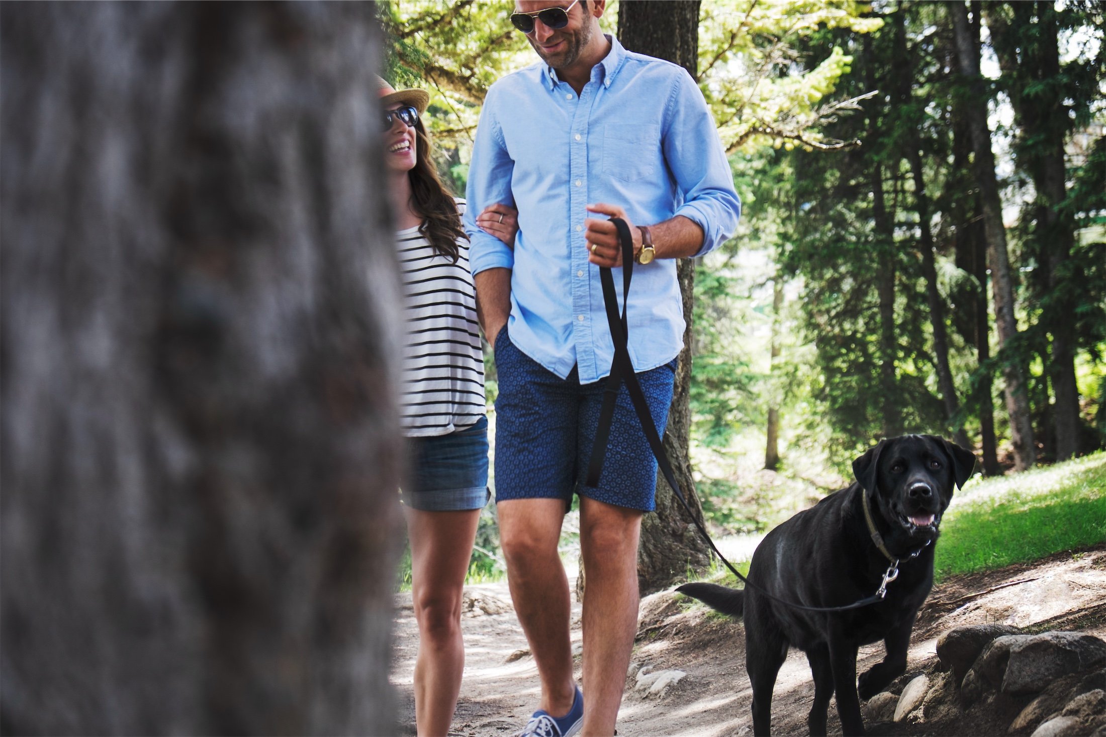 couple walking with black dog in woods