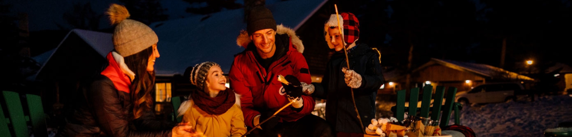 Family of four, sitting around an open fire roasting marshmallows at Jasper Park Lodge for Family Day