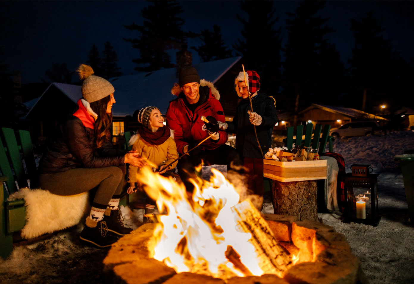 Family of four, sitting around an open fire roasting marshmallows at Jasper Park Lodge for Family Day