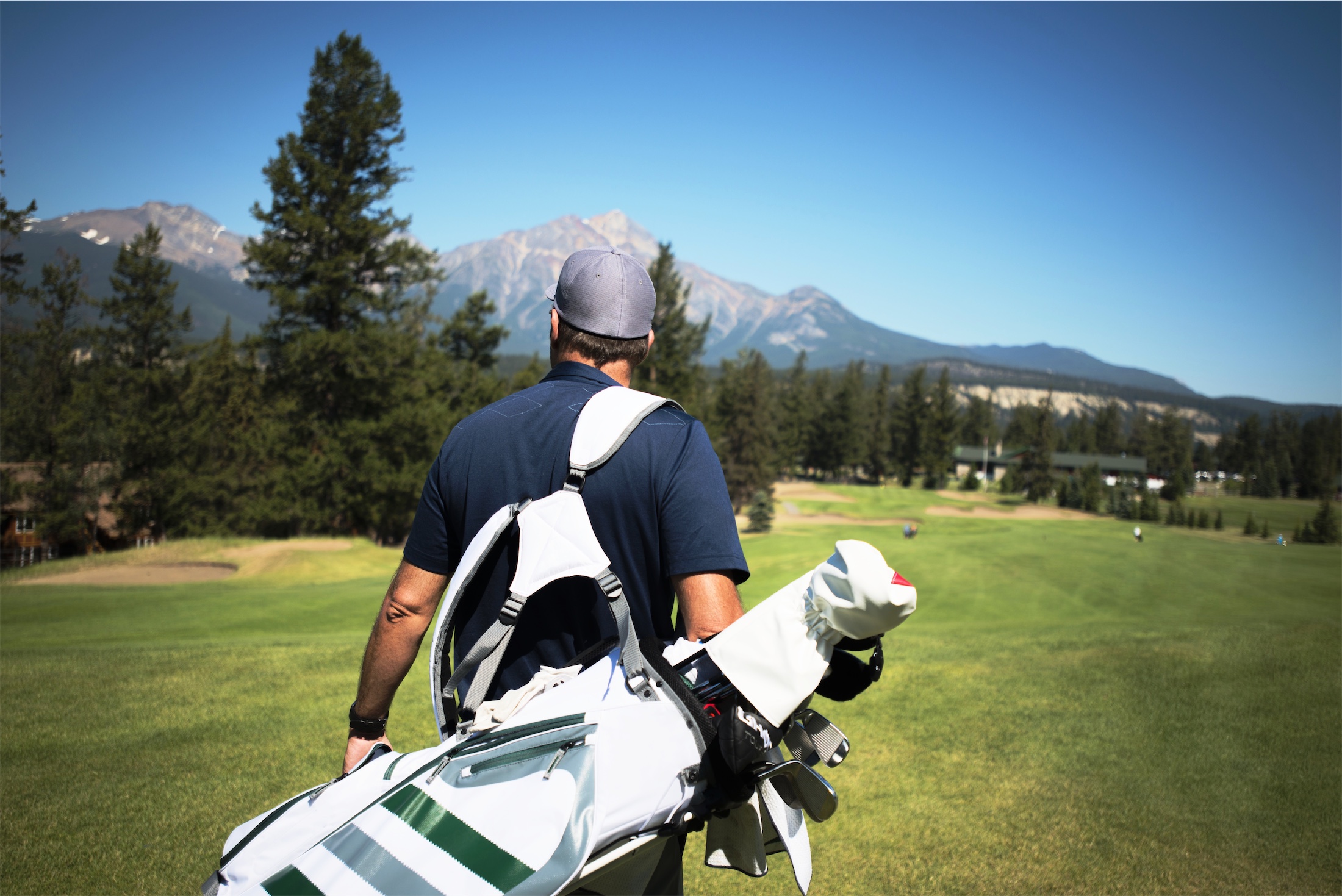 man carrying golf bag on golf course