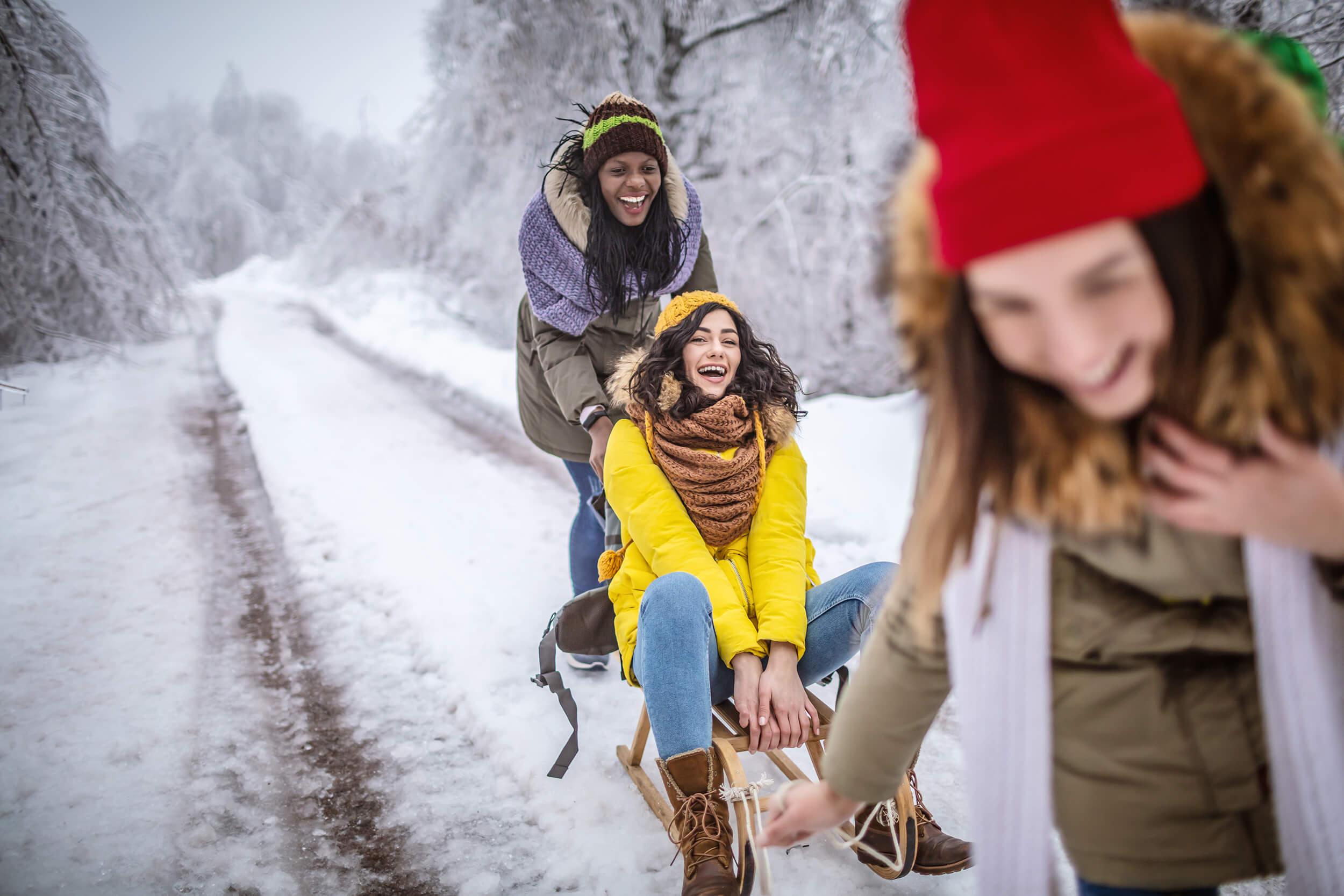 three girl friends pulling each other on sled