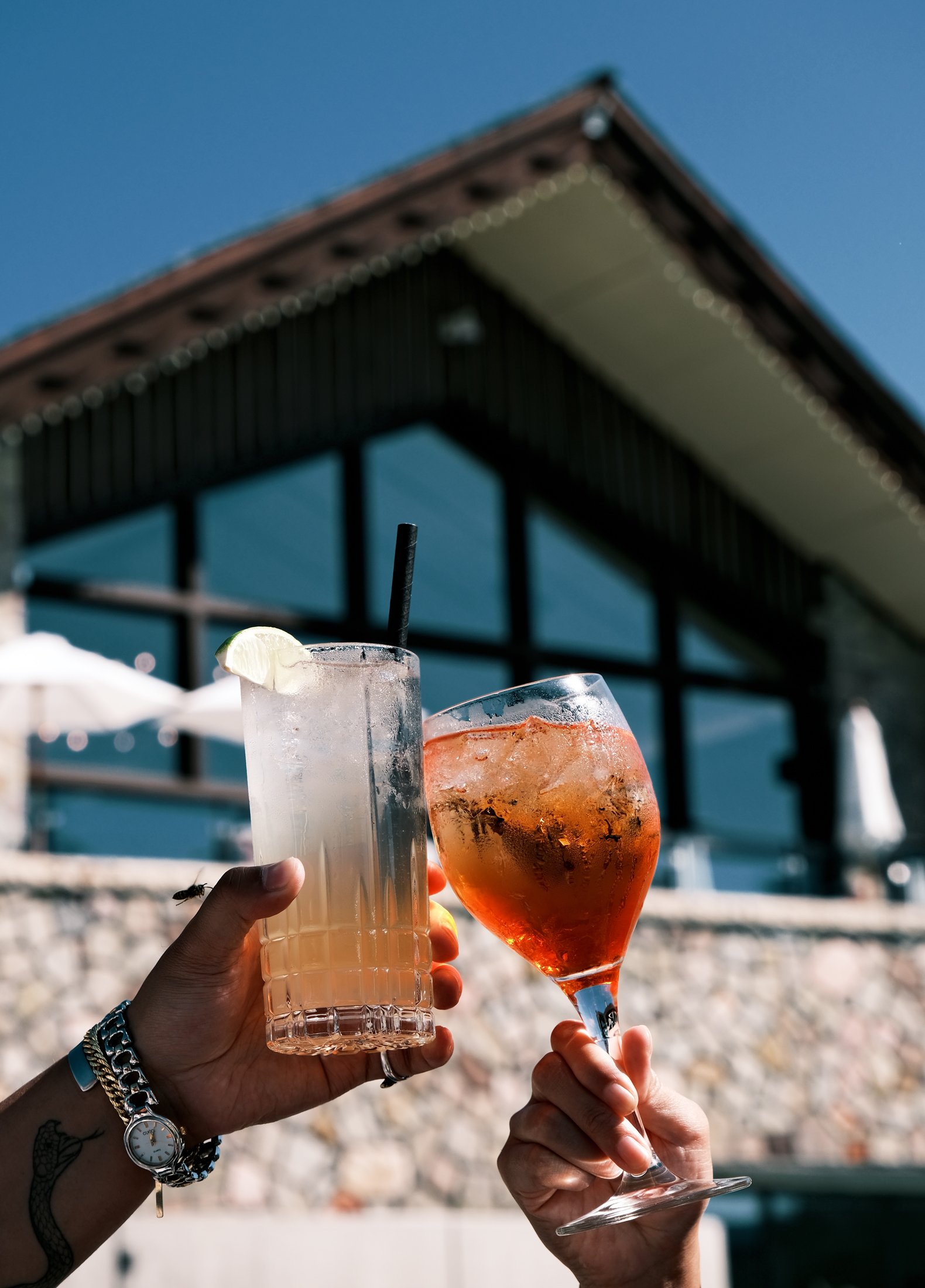 Two drink glasses cheers each other with Jasper Park Lodge in the background.