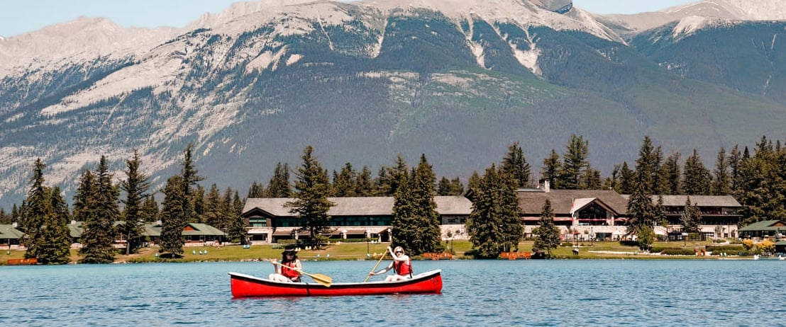 two women rowing in canoe by mountains