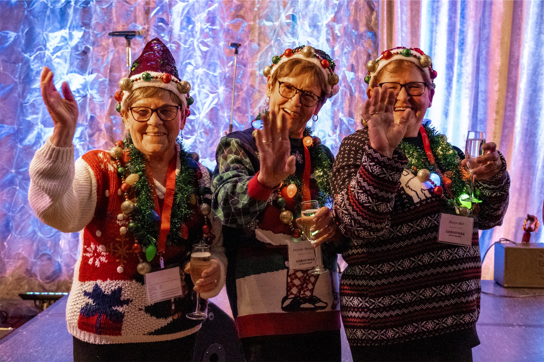 three older women drinking champagne with holiday sweaters