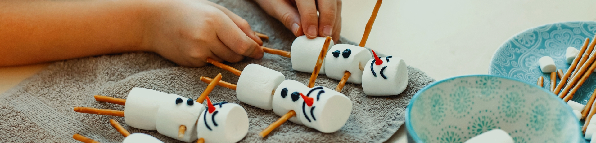 Two brothers drink cocoa and make snowmen with marshmallows and crispy sticks at Family Arts and Crafts at Jasper Park Lodge