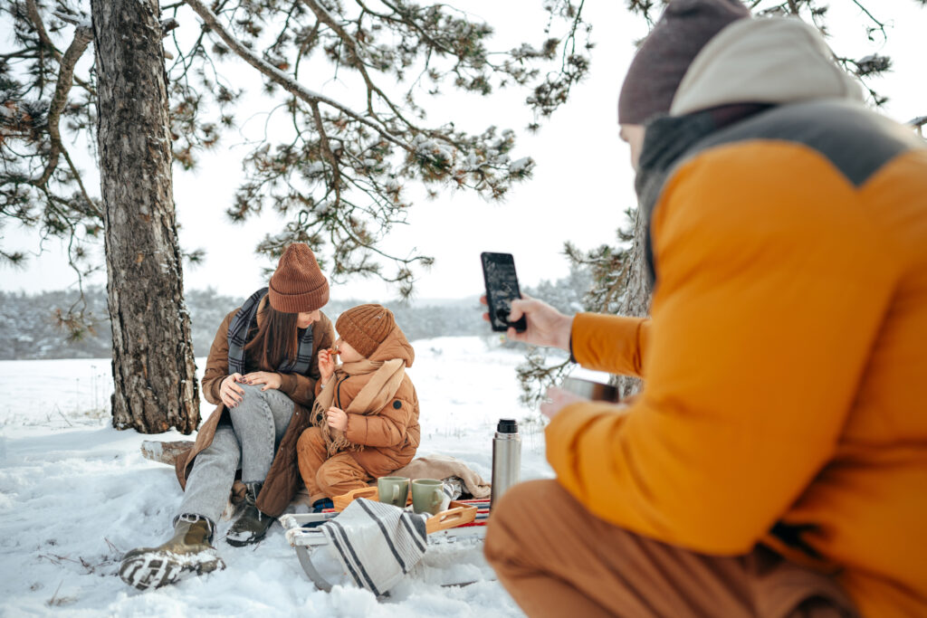 Happy family with cups of hot tea spending time together in winter forest, close up