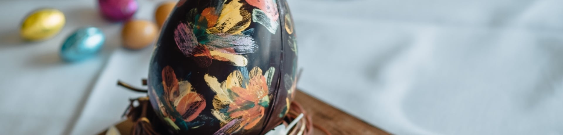 Chocolate Easter egg painted with colours sitting on a wooden board with JPL engraved on it from Jasper Park Lodge