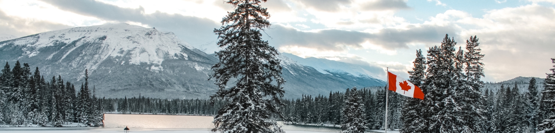 An outdoor pool overlooking the mountain range of Jasper Park Lodge in Jasper National Park. Snow covers the ground around the blue pool.