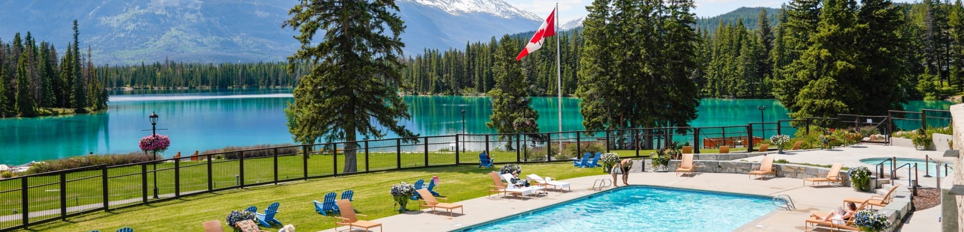 Outdoor pool surrounded by mountains in the summer at Fairmont Jasper Park Lodge.