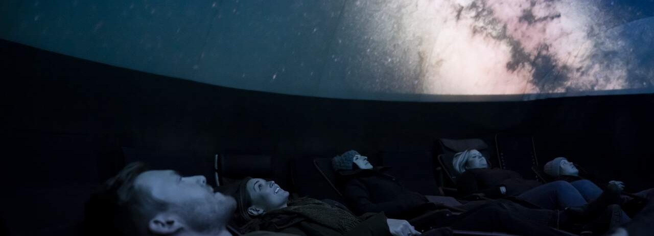 Young couple viewing projected sky in planetarium