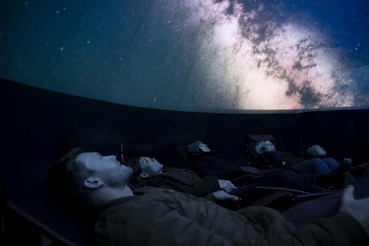 Young couple viewing projected sky in planetarium