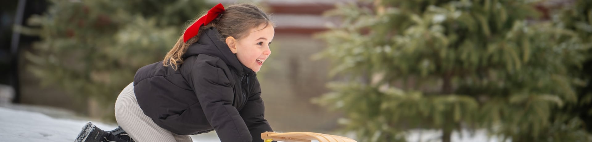 A small girl toboggans down a hill of snow at Fairmont Jasper Park Lodge.