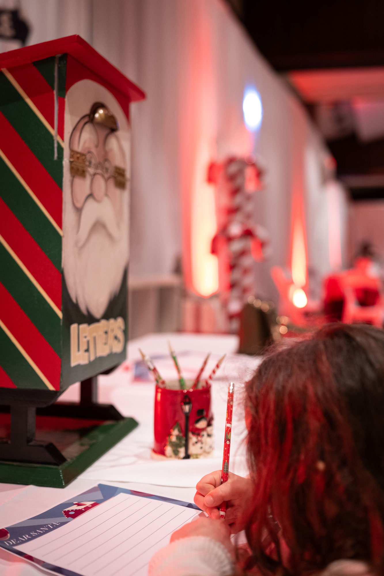 Small girl writes a letter to Santa to place in the letters to Santa mailbox at Christmas at The Lodge at Fairmont Jasper Park Lodge.