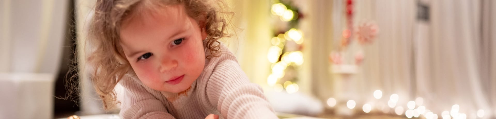 Small child places a piece on a checkerboard at Christmas at The Lodge at Fairmont Jasper Park Lodge.