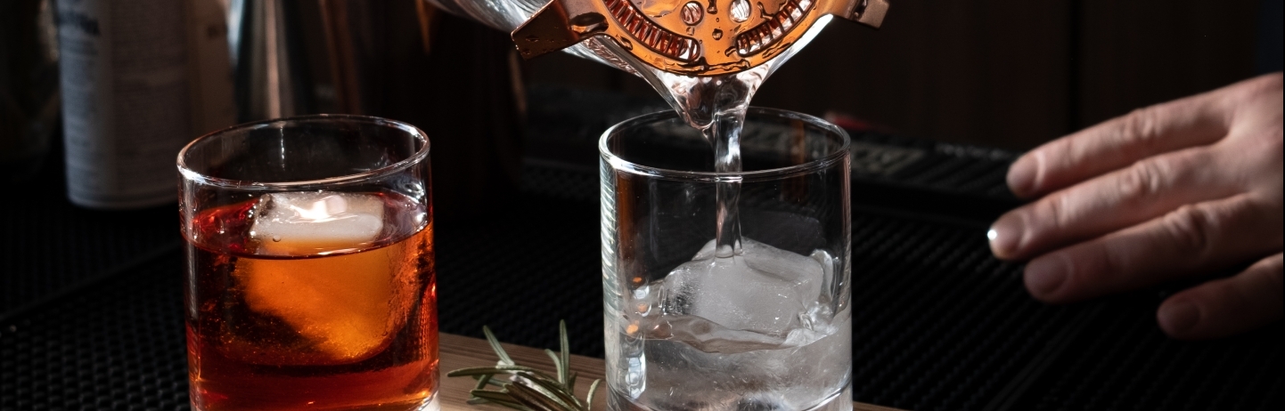 a bartender strains a drink into a short class at Emerald Lounge at Fairmont Jasper Park Lodge