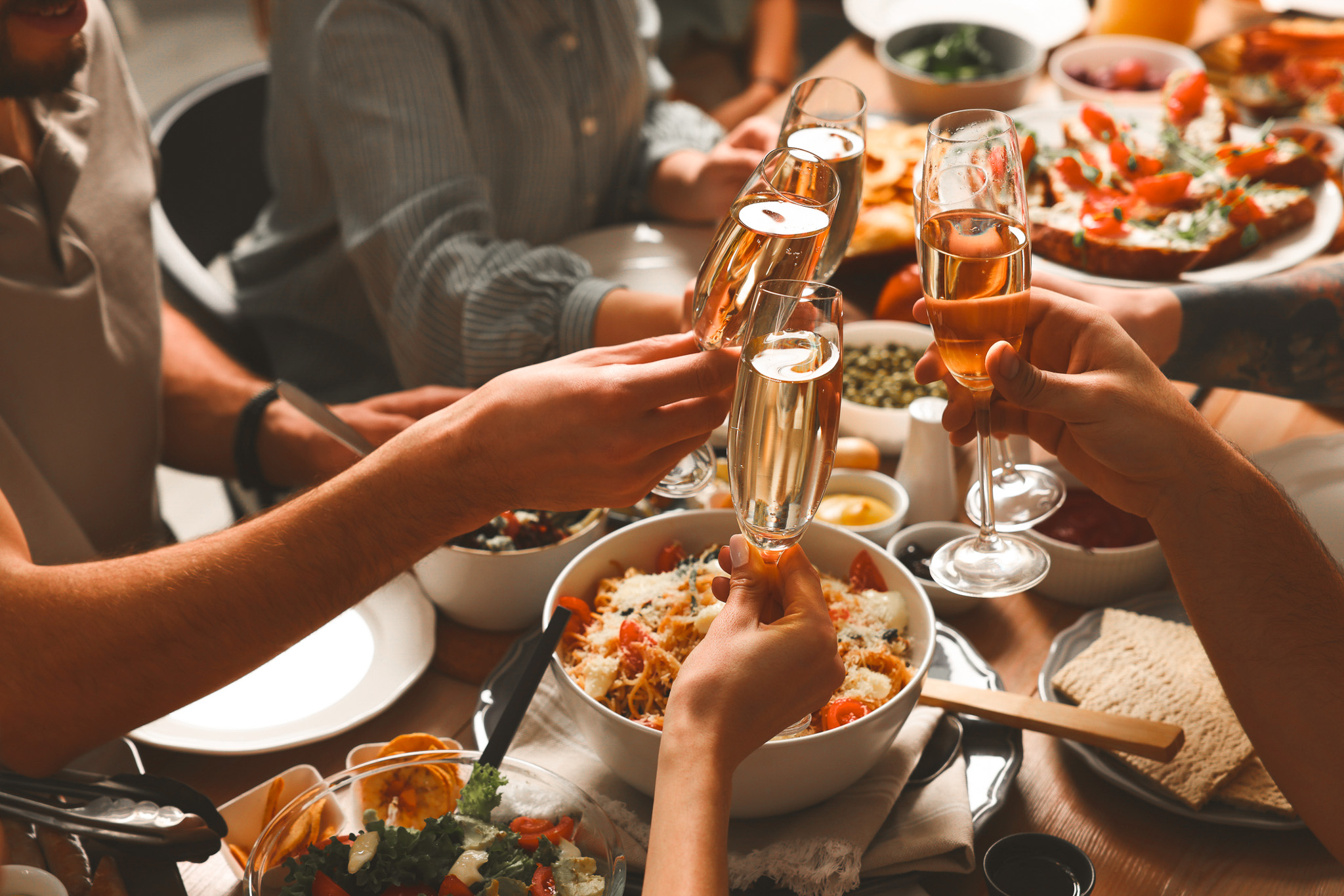 Group of people clinking glasses with champagne during brunch at table, closeup