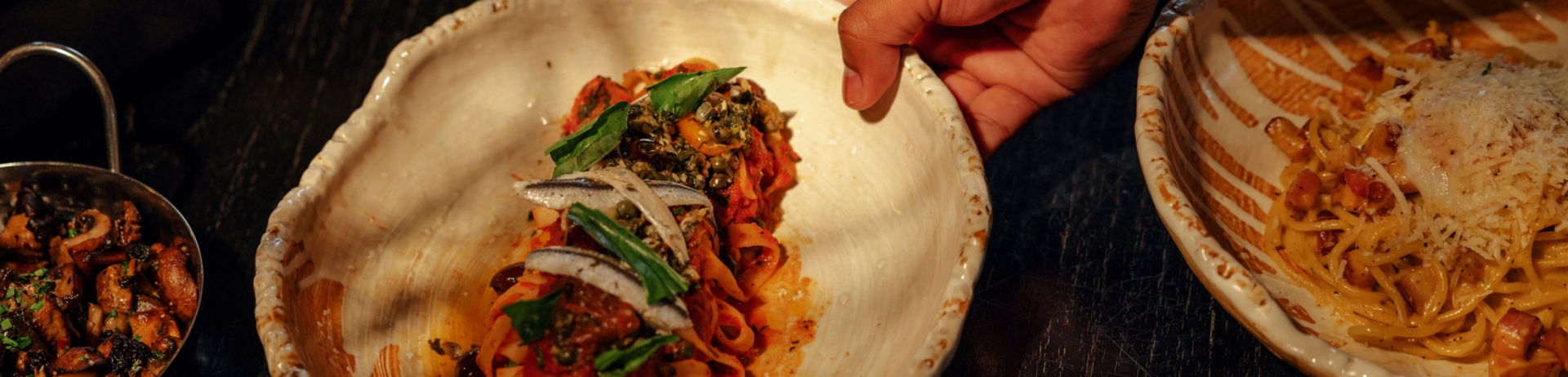 Photo of plated pasta dishes with the center plate being picked up