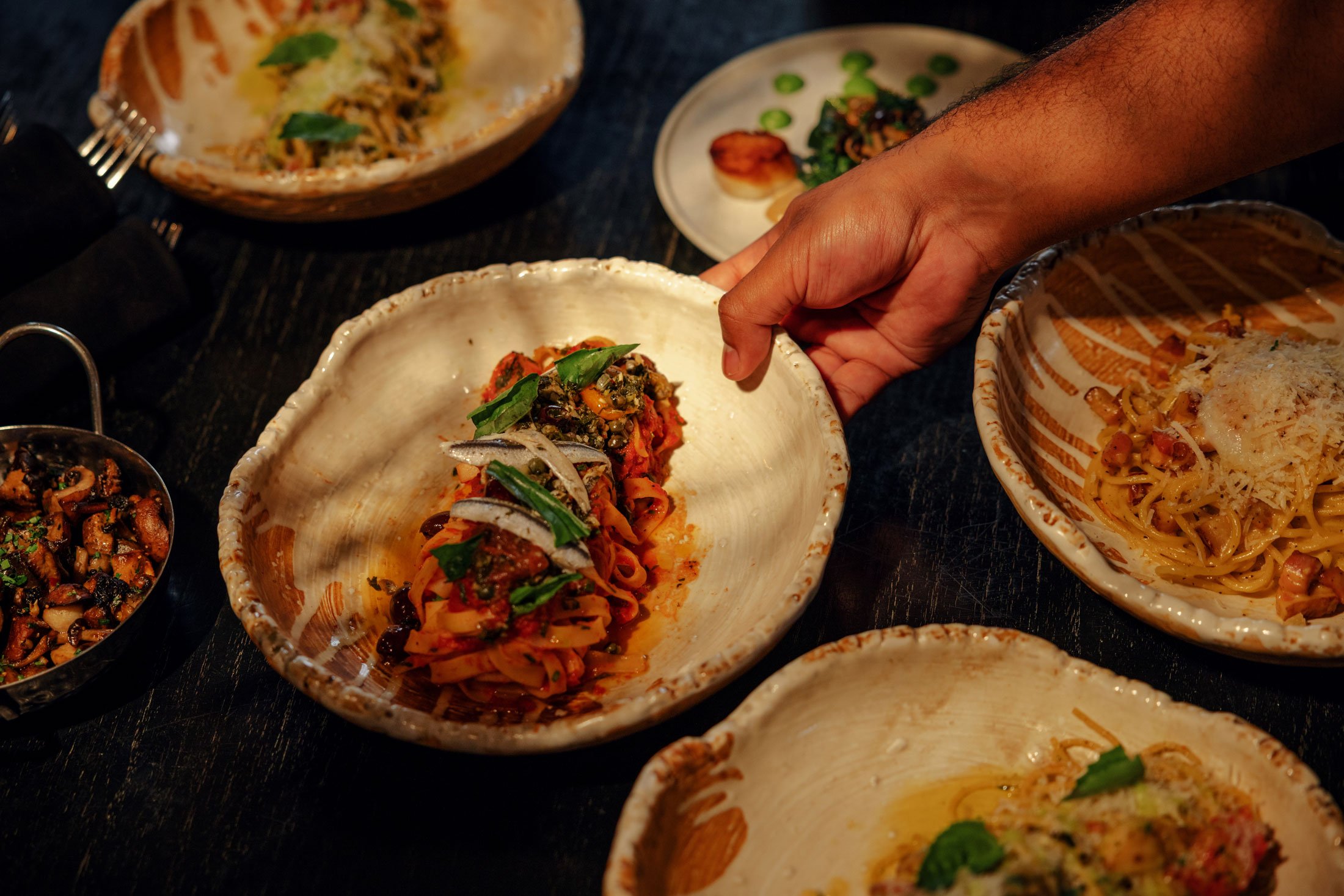 Photo of plated pasta dishes with the center plate being picked up