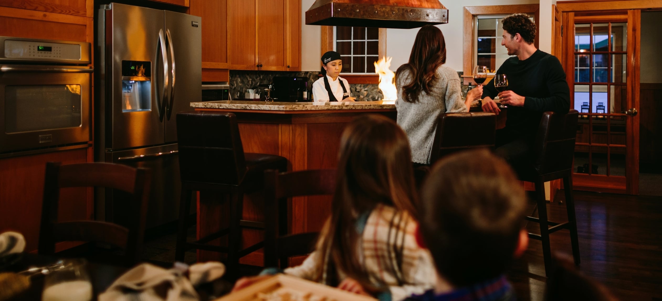 Family enjoying time in cabin with a chef preparing dinner