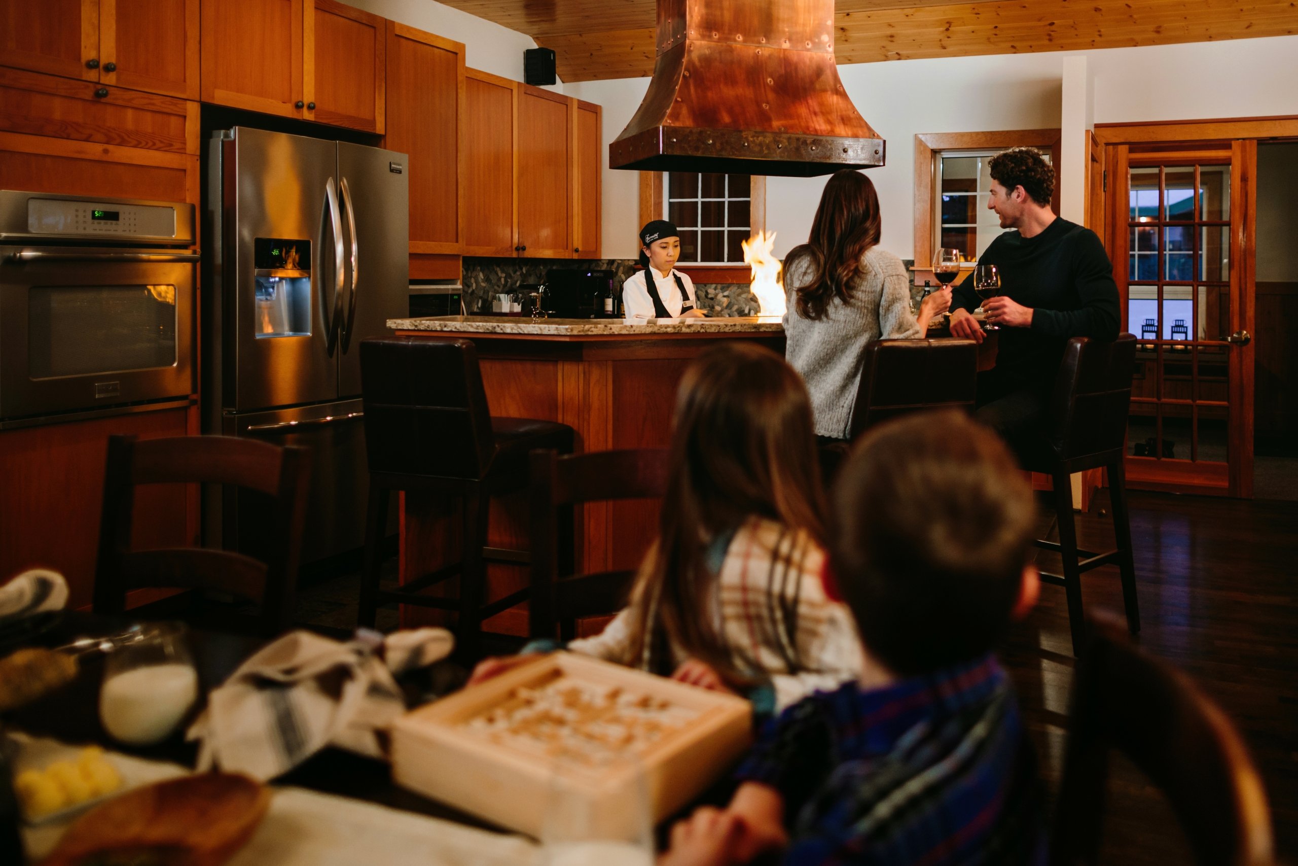 Family enjoying time in cabin with a chef preparing dinner