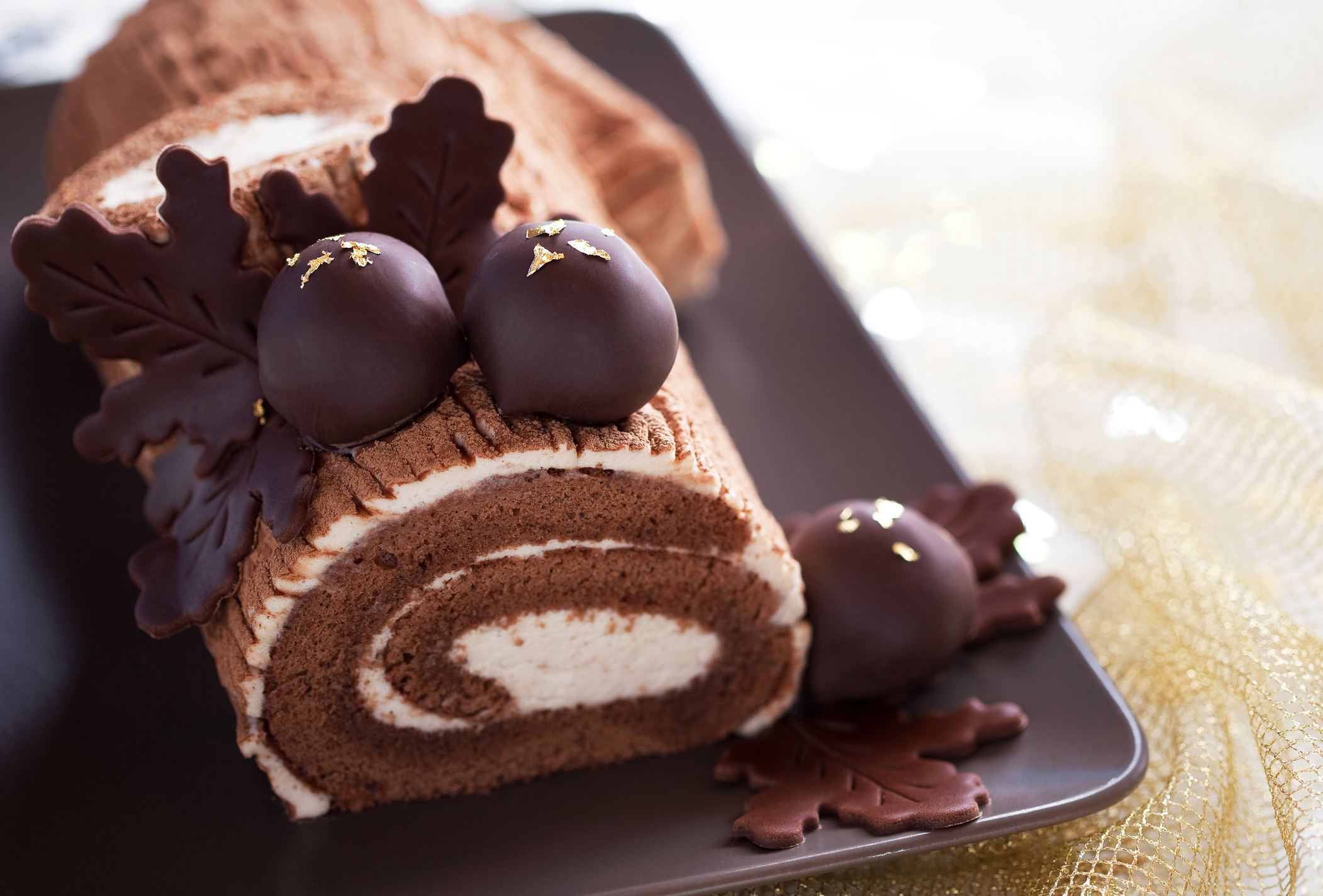 Traditional Christmas Yule Log cake decorated with chocolate chestnuts, selective focus