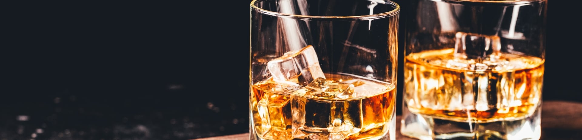 2 Glasses of Whiskey on a wooden countertop, served on the rocks.