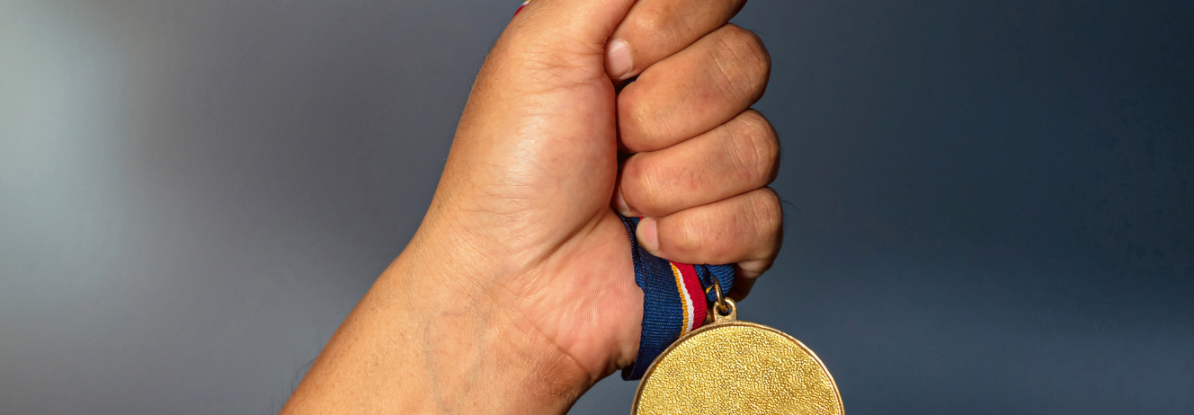 Hand holding up a gold medal