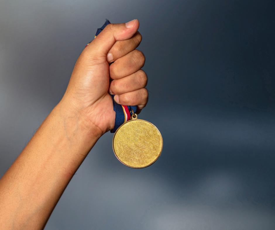 Hand holding up a gold medal