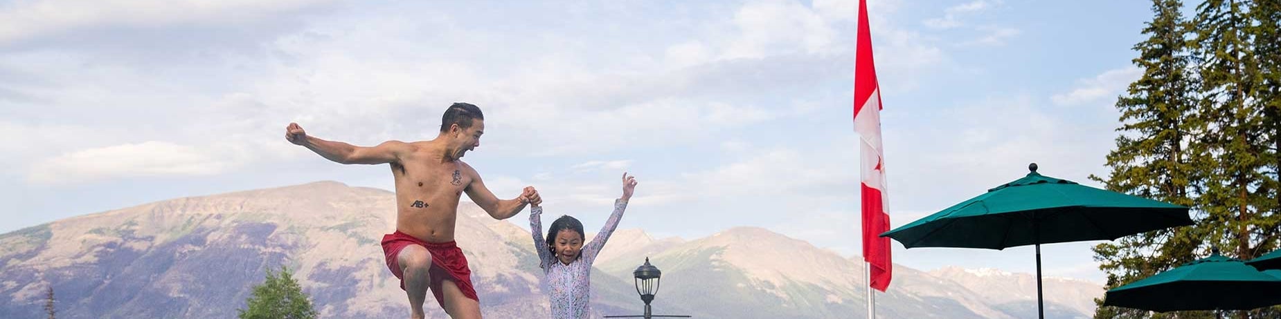 Father and daughter jumping in an outdoor pool