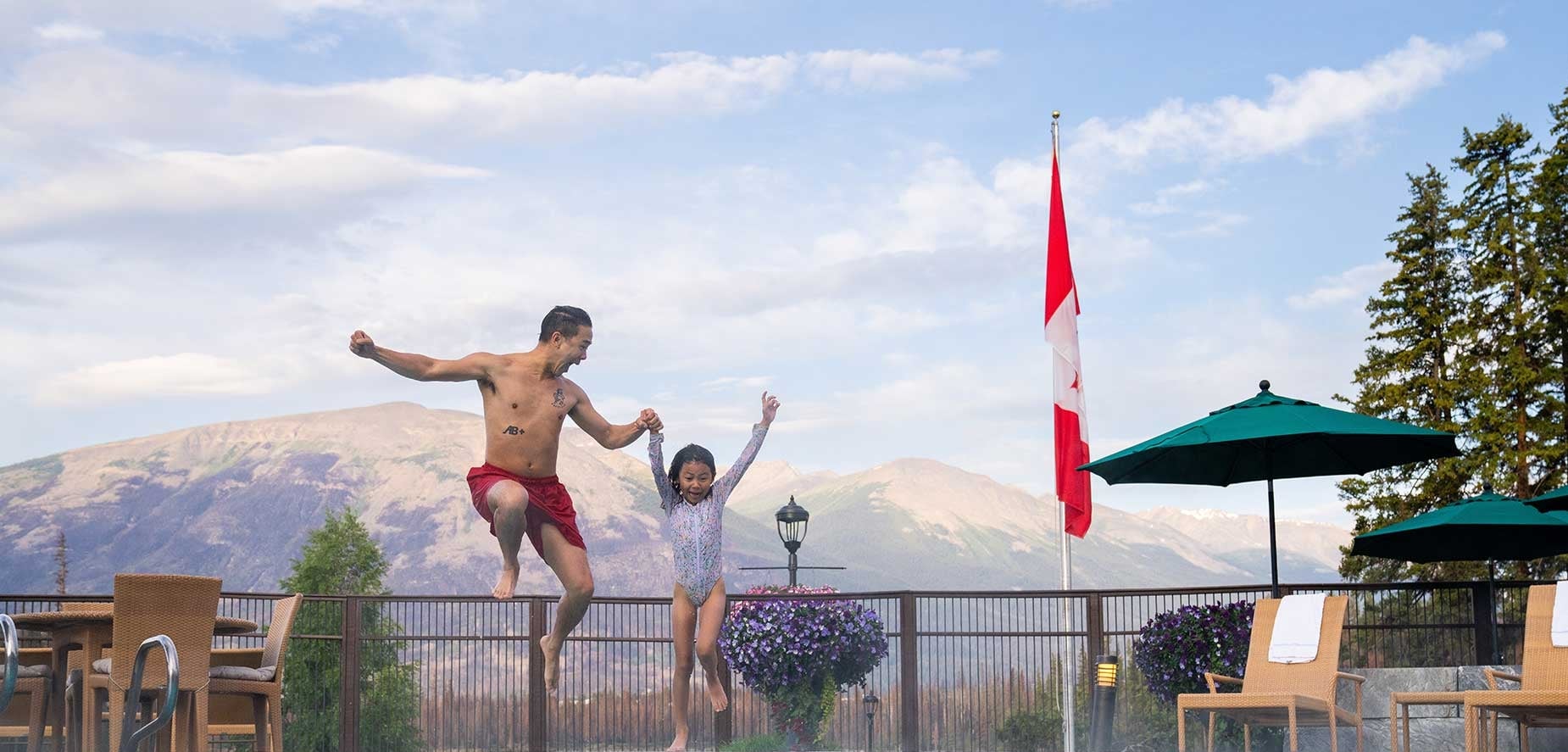 Father and daughter jumping in an outdoor pool