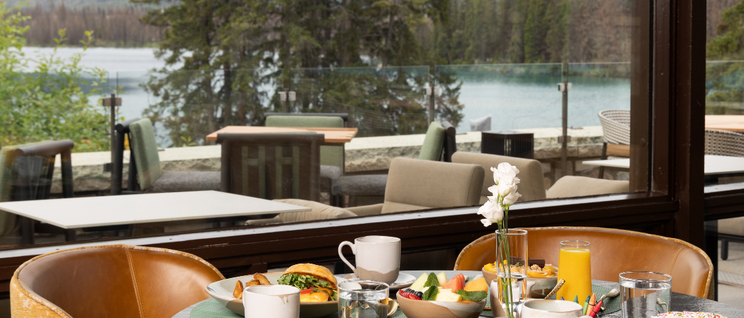 A meal on a table in a restaurant in front of a window with a mountain and alpine view.