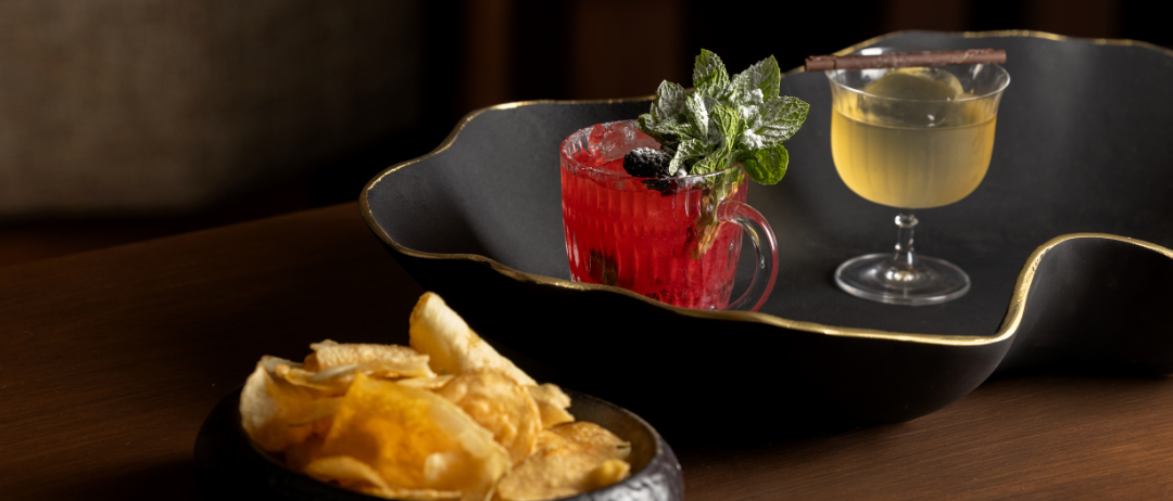 A picture of two cocktails on a table with chips.