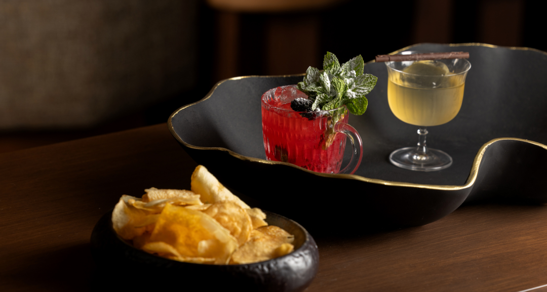 A picture of two cocktails on a table with chips.