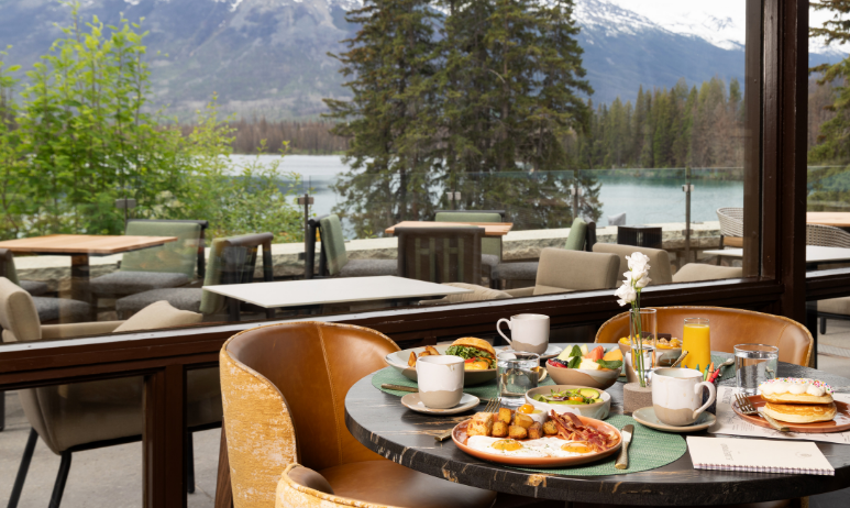 A meal on a table in a restaurant in front of a window with a mountain and alpine view.