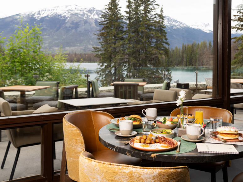 A meal on a table in a restaurant in front of a window with a mountain and alpine view.