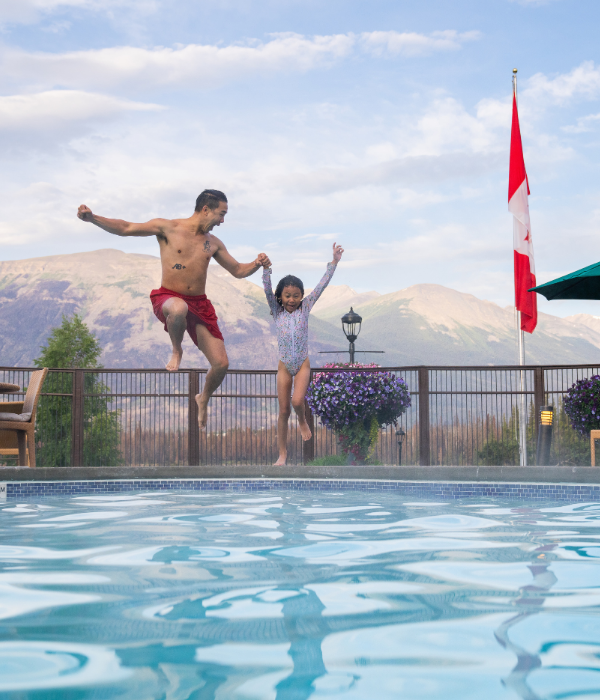 A father and daughter jumping into a swimming pool.