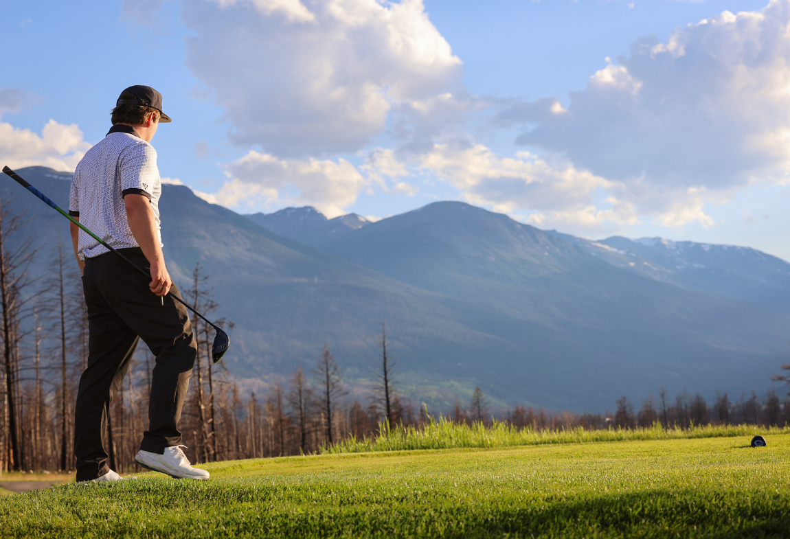Man golfing in a mountain setting.